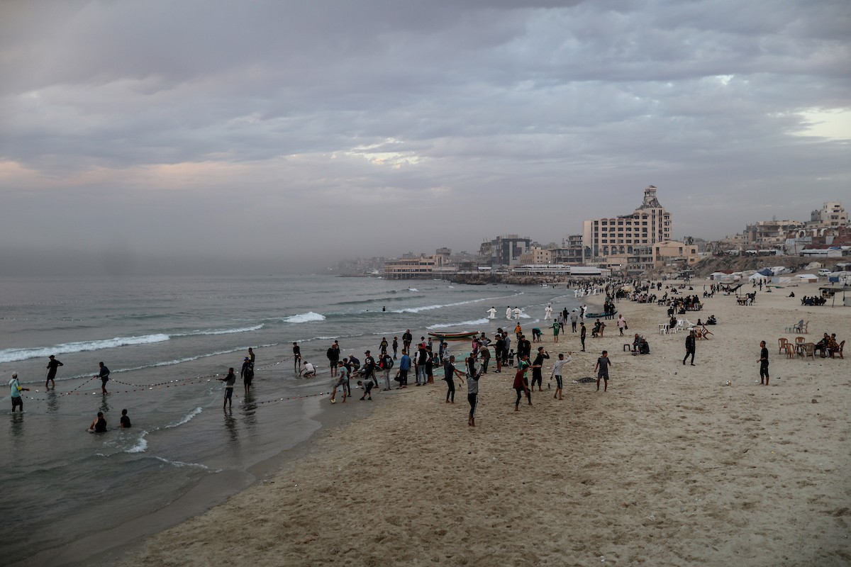 يقضي فلسطينيون نازحون وقتًا على الشاطئ مقابل خيامهم الممتدة على طول ميناء غزة، في غزة، 5 ديسمبر/كانون الأول 2025. تصوير: عمر أشتوي