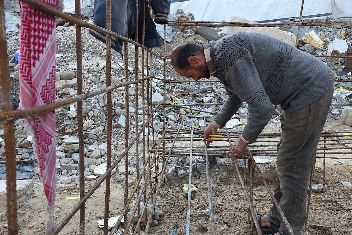 الفلسطيني هشام أبو عية يبني مأوى مؤقت لعائلته المكونة من ثمانية أفراد باستخدام قضبان حديدية استخرجها من أنقاض منزله الذي دُمر في هجمات إسرائيلية بمنطقة بطن السمين في خان يونس،  19 ديسمبر/كانون الأول 2025. تصوير: طارق محمد/ (APA )