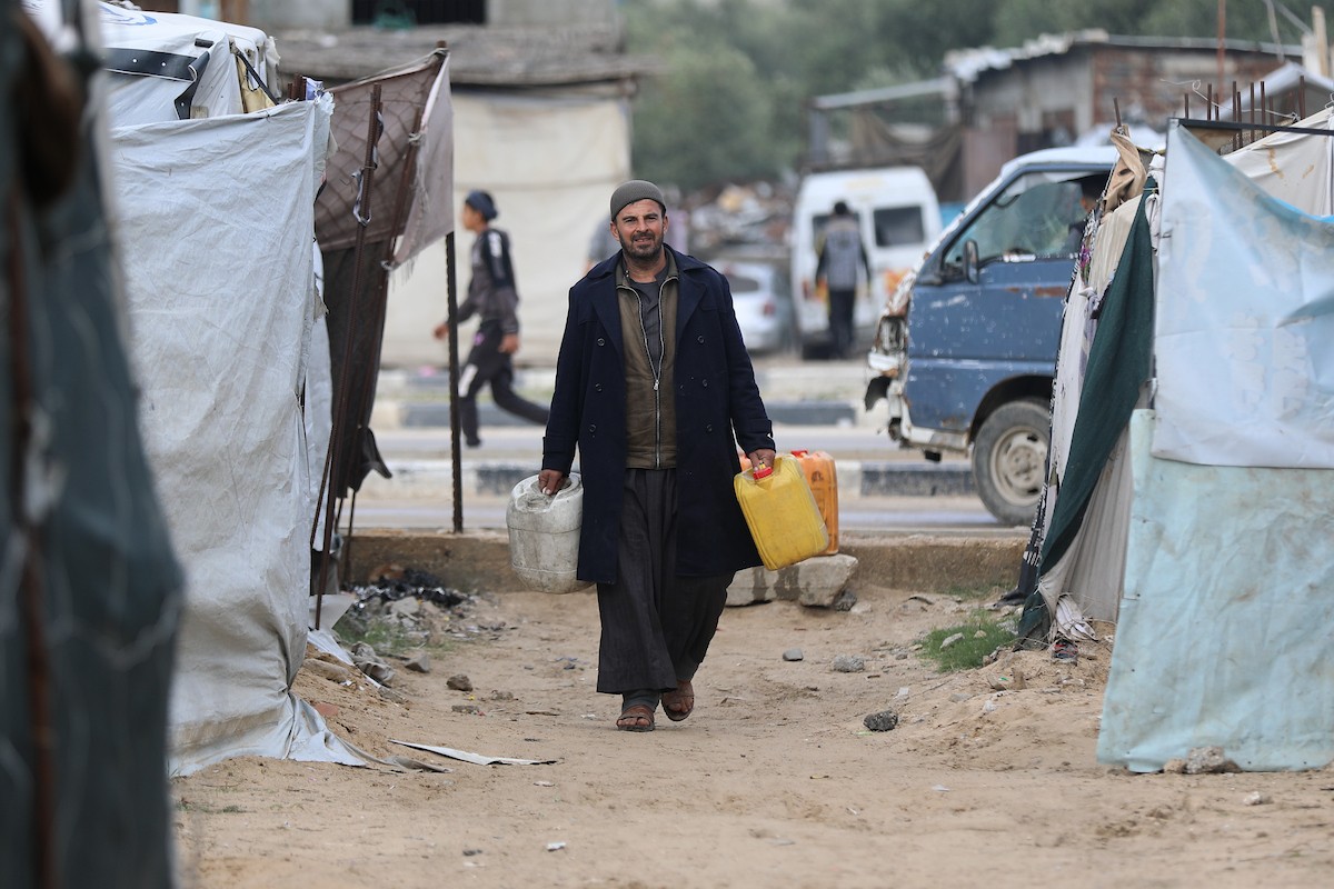 يتجمع الفلسطينيون لتلقي مياه الشرب مجانًا في مخيم البريج للاجئين، في ظل تفاقم أزمة نقص المياه وتدهور البنية التحتية، 21 ديسمبر/كانون الأول 2025. صورة: رمزي أبو عامر