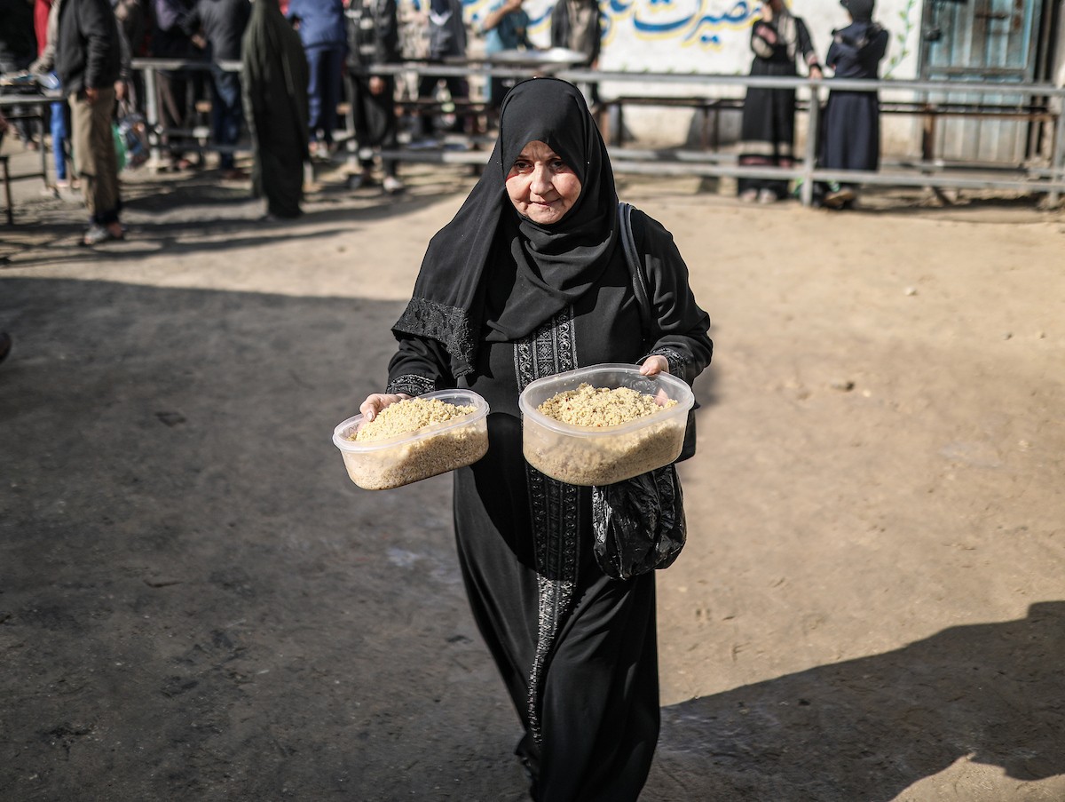 يصطفّ فلسطينيون لتلقّي الطعام من مطبخ خيري في تجمع للنازحين بمخيم النصيرات للاجئين، وسط قطاع غزة. ١٧ ديسمبر/كانون الأول ٢٠٢٥. تصوير: رمزي أبو عامر / (apa)