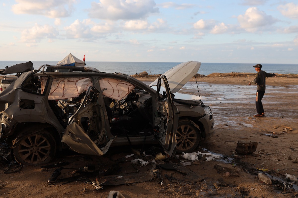 فلسطينيون يتفقدون موقع غارة إسرائيلية استهدفت سيارة على شارع لرشيد غرب مدينة غزة، 13 ديسمبر/كانون الأول 2025. صور: عمر أشتوي