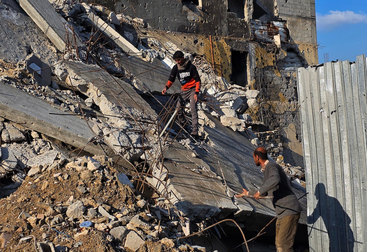 الفلسطيني هشام أبو عية يبني مأوى مؤقت لعائلته المكونة من ثمانية أفراد باستخدام قضبان حديدية استخرجها من أنقاض منزله الذي دُمر في هجمات إسرائيلية بمنطقة بطن السمين في خان يونس،  19 ديسمبر/كانون الأول 2025. تصوير: طارق محمد/ (APA )