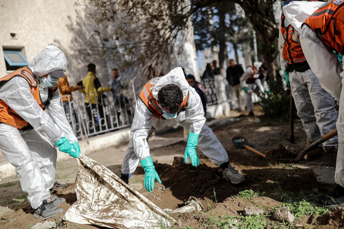 منقذون ومتطوعون فلسطينيون يستخرجون جثث ضحايا الحرب من مقبرة مؤقتة داخل المستشفى العربي المعمداني بمدينة غزة، ليعاد دفنها