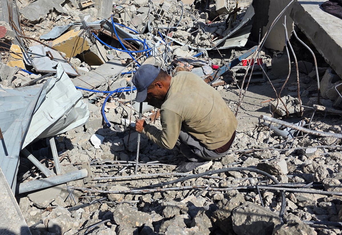 في خان يونس، جنوب قطاع غزة، يقوم أصحاب المتاجر الفلسطينيون بإزالة الأنقاض بأيديهم، ويعيدون بناء متاجرهم المتضررة باستخدام الحجارة والطين الأحمر، 27 ديسمبر/كانون الأول 2025 (صورة: طارق محمد)