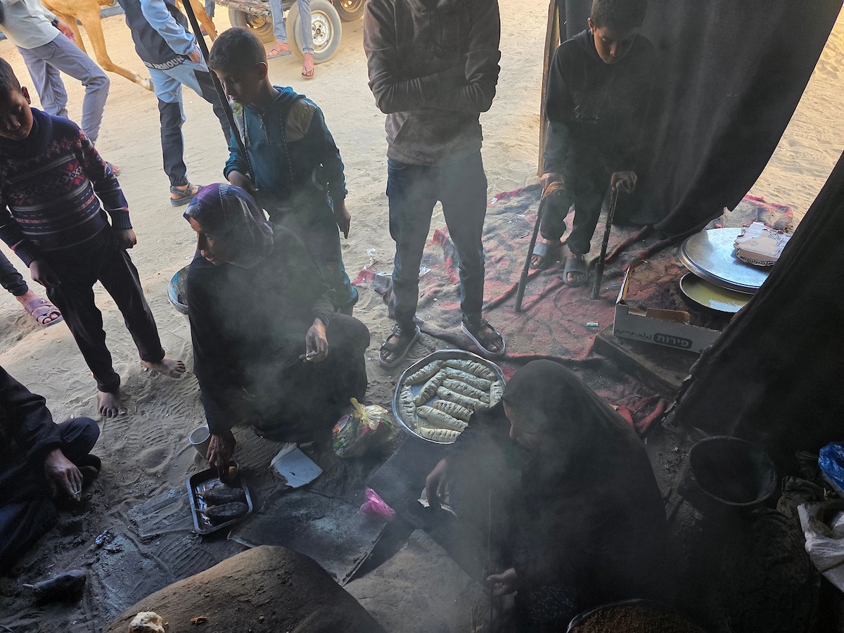 يتجمع فلسطينيون حول أفران طينية مؤقتة لطهي الطعام في قطاع غزة، بعد عشرة أسابيع من وقف إطلاق النار، في ظل شحّ غاز الطهي بسبب القيود الإسرائيلية على دخوله إلى القطاع