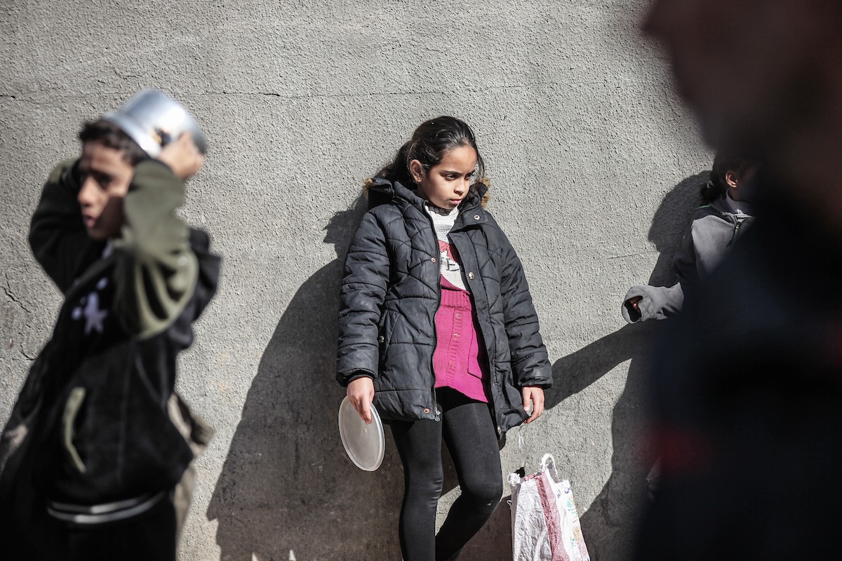 يتلقى فلسطينيون في مخيم النصيرات وسط قطاع غزة وجبات ساخنة من جمعية خيرية تُعنى بالنازحين جراء الهجمات الإسرائيلية، بينما يتجمع حشد كبير، يضم نساءً وأطفالاً، خلال عملية التوزيع، في 30 ديسمبر/كانون الأول 2025. صورة: معز صالحي