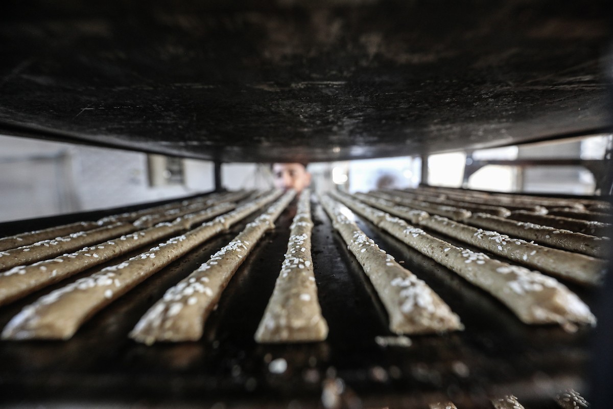 عمال فلسطينيون يعيدون تشغيل أحد أقدم المخابز في مخيم النصيرات للاجئين بعد إغلاقه لمدة عامين بسبب الحرب (25).jpg