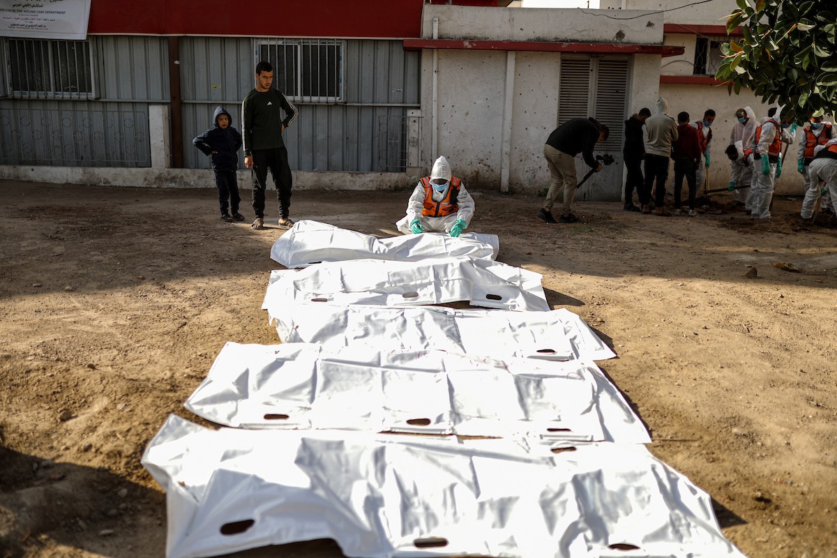 منقذون ومتطوعون فلسطينيون يستخرجون جثث ضحايا الحرب من مقبرة مؤقتة داخل المستشفى العربي المعمداني بمدينة غزة، ليعاد دفنها