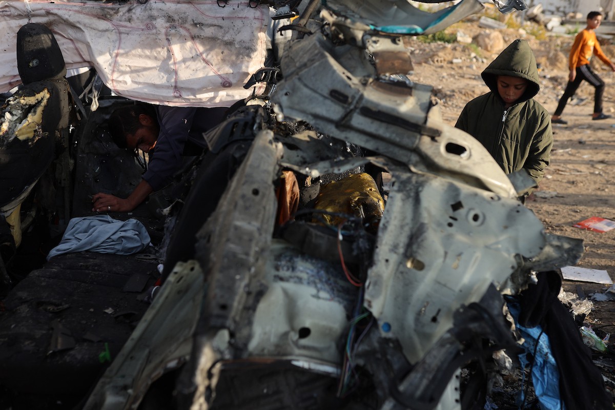 فلسطينيون يتفقدون موقع غارة إسرائيلية استهدفت سيارة على شارع لرشيد غرب مدينة غزة، 13 ديسمبر/كانون الأول 2025. صور: عمر أشتوي