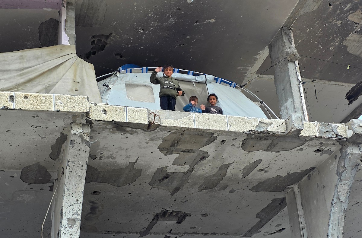 عائلة فلسطينية تحتمي من برد الشتاء القارس في خيمة نصبتها فوق منزلها المدمر قرب الخط الأصفر في خان يونس، جنوب قطاع غزة، ١٧ ديسمبر/كانون الأول ٢٠٢٥. تصوير: طارق محمد/وكالة الأنباء الفلسطينية (APA )