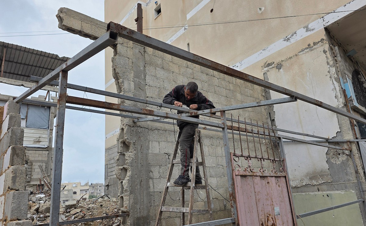 في خان يونس، جنوب قطاع غزة، يقوم أصحاب المتاجر الفلسطينيون بإزالة الأنقاض بأيديهم، ويعيدون بناء متاجرهم المتضررة باستخدام الحجارة والطين الأحمر، 27 ديسمبر/كانون الأول 2025 (صورة: طارق محمد)