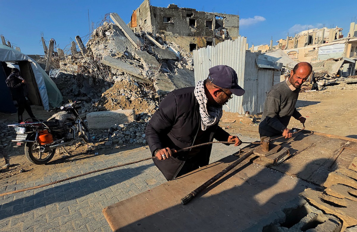 الفلسطيني هشام أبو عية يبني مأوى مؤقت لعائلته المكونة من ثمانية أفراد باستخدام قضبان حديدية استخرجها من أنقاض منزله الذي دُمر في هجمات إسرائيلية بمنطقة بطن السمين في خان يونس،  19 ديسمبر/كانون الأول 2025. تصوير: طارق محمد/ (APA )