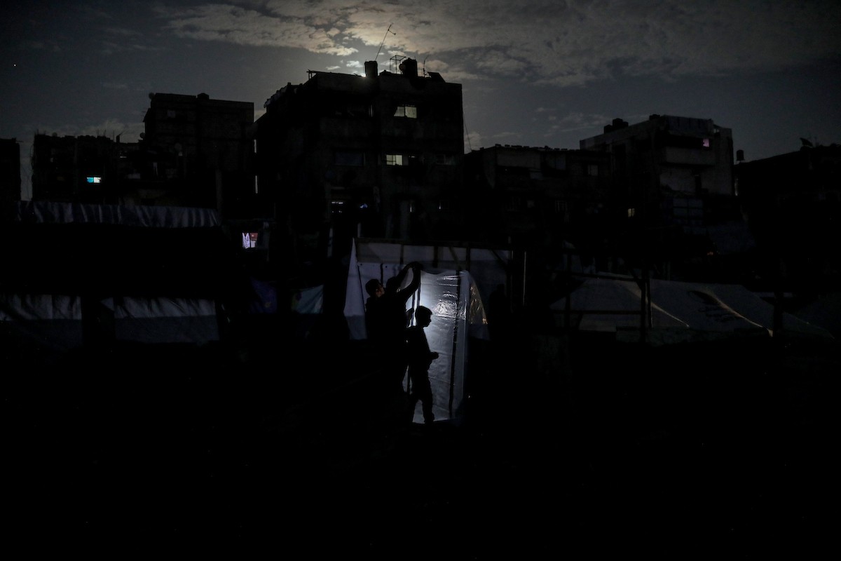 يعيش الفلسطينيون حياتهم اليومية ليلاً في خيام نصبت فوق أنقاض المباني المدمرة في حي الشيخ رضوان وسط مدينة غزة، 5 ديسمبر/كانون الأول 2025.تصوير: عمر أشتوي