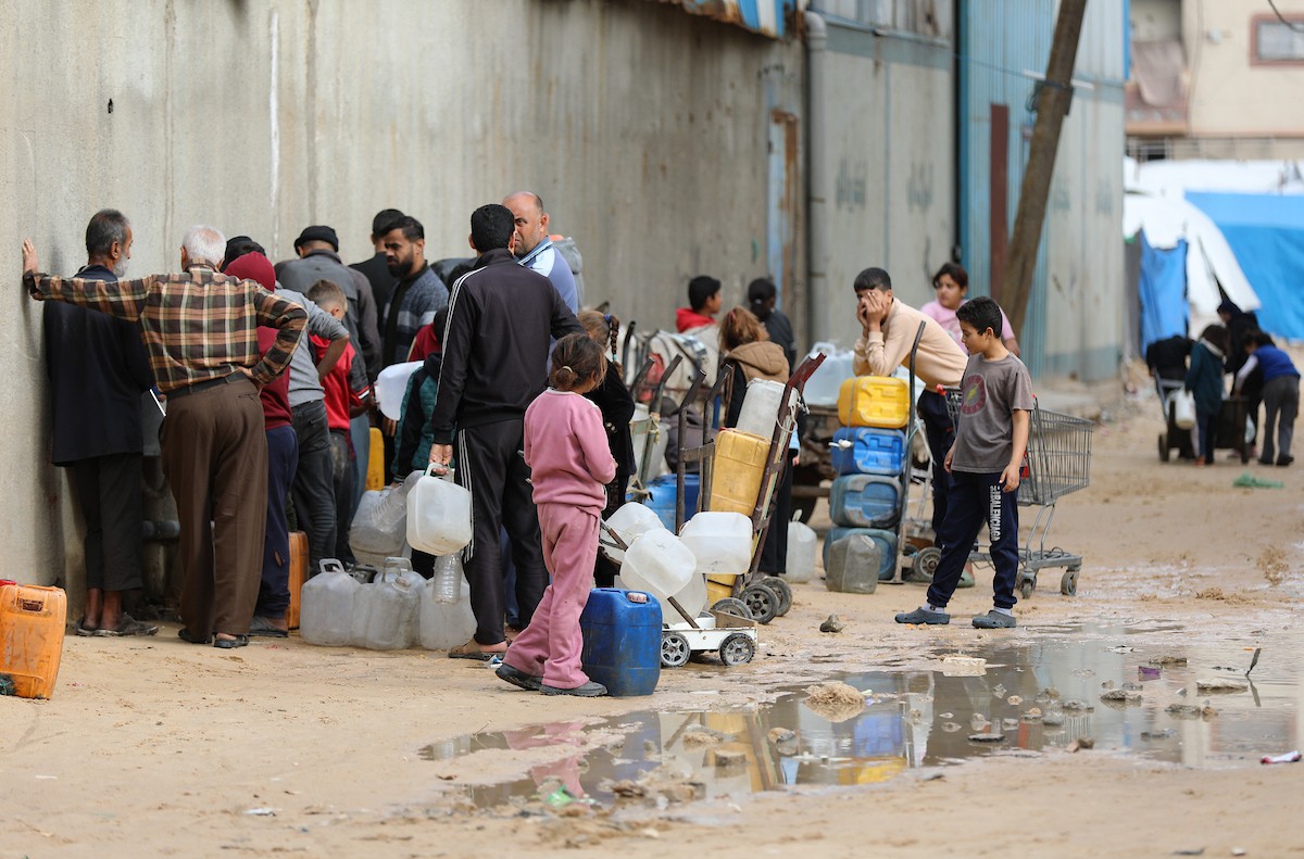 يتجمع الفلسطينيون لتلقي مياه الشرب مجانًا في مخيم البريج للاجئين، في ظل تفاقم أزمة نقص المياه وتدهور البنية التحتية، 21 ديسمبر/كانون الأول 2025. صورة: رمزي أبو عامر