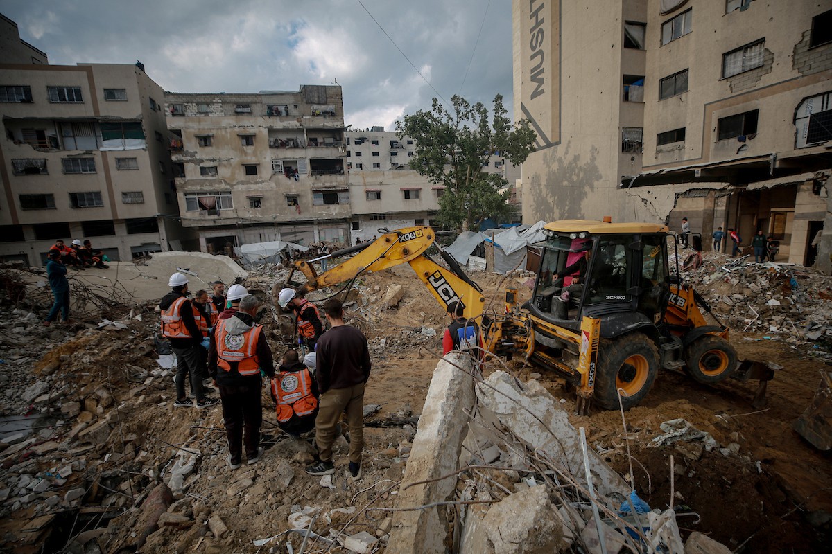 عمال الدفاع المدني الفلسطيني يبحثون عن جثث في مبنى منهار يعود لعائلة سالم، استُهدف بغارات إسرائيلية في بداية الحرب، في شارع الجلاء بمدينة غزة، يوم الاثنين 15 ديسمبر/كانون الأول 2025. صورة: عمر أشتوي