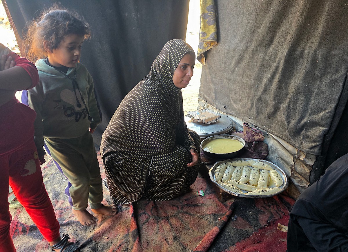 يتجمع فلسطينيون حول أفران طينية مؤقتة لطهي الطعام في قطاع غزة، بعد عشرة أسابيع من وقف إطلاق النار، في ظل شحّ غاز الطهي بسبب القيود الإسرائيلية على دخوله إلى القطاع
