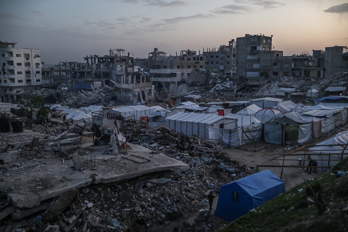 يعيش الفلسطينيون حياتهم اليومية ليلاً في خيام نصبت فوق أنقاض المباني المدمرة في حي الشيخ رضوان وسط مدينة غزة، 5 ديسمبر/كانون الأول 2025.تصوير: عمر أشتوي