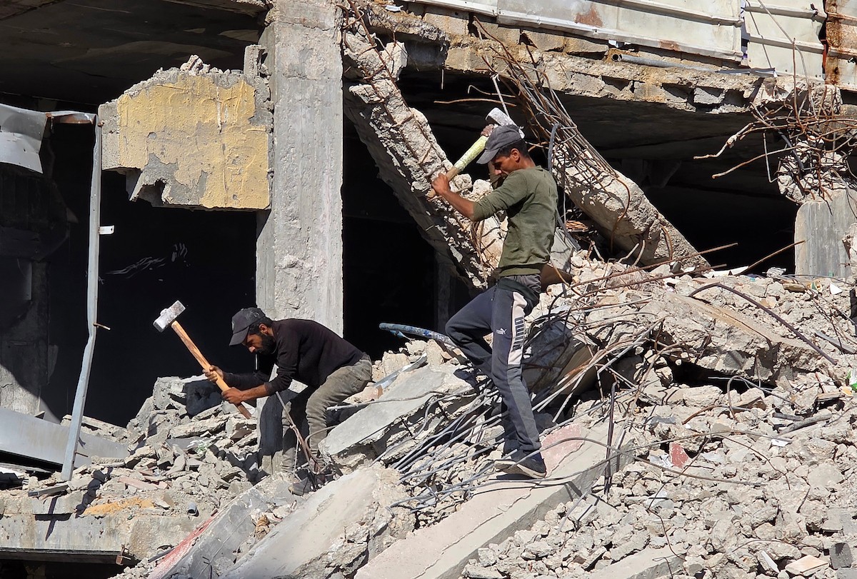 في خان يونس، جنوب قطاع غزة، يقوم أصحاب المتاجر الفلسطينيون بإزالة الأنقاض بأيديهم، ويعيدون بناء متاجرهم المتضررة باستخدام الحجارة والطين الأحمر، 27 ديسمبر/كانون الأول 2025 (صورة: طارق محمد)