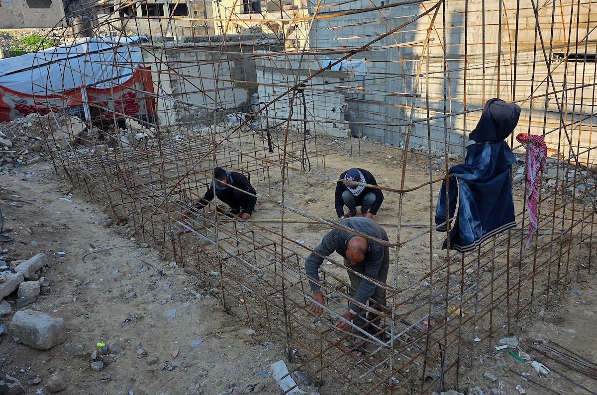 الفلسطيني هشام أبو عية يبني مأوى مؤقت لعائلته المكونة من ثمانية أفراد باستخدام قضبان حديدية استخرجها من أنقاض منزله الذي دُمر في هجمات إسرائيلية بمنطقة بطن السمين في خان يونس،  19 ديسمبر/كانون الأول 2025. تصوير: طارق محمد/ (APA )