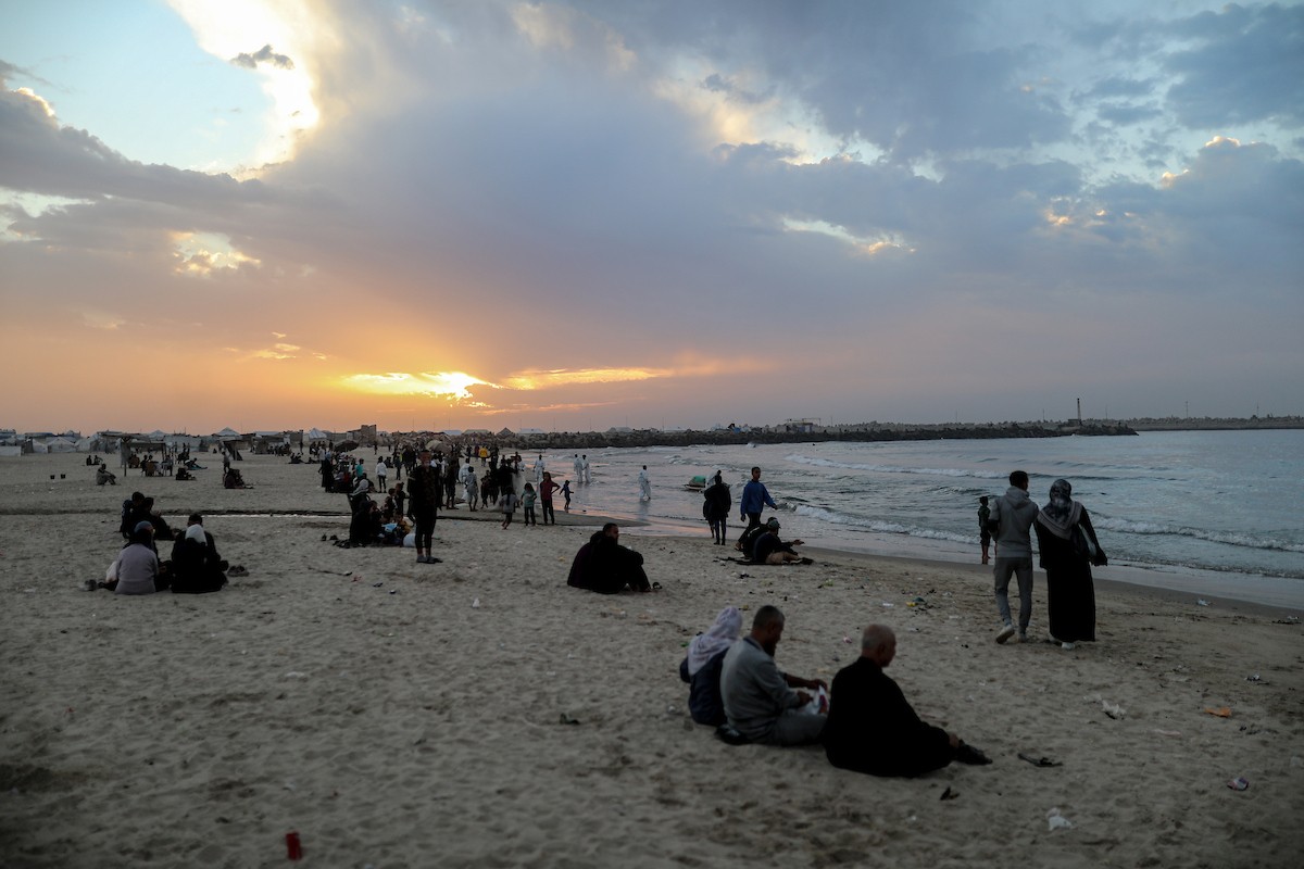 يقضي فلسطينيون نازحون وقتًا على الشاطئ مقابل خيامهم الممتدة على طول ميناء غزة، في غزة، 5 ديسمبر/كانون الأول 2025. تصوير: عمر أشتوي