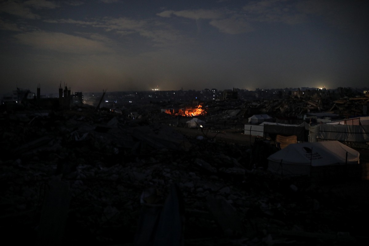 يعيش الفلسطينيون حياتهم اليومية ليلاً في خيام نصبت فوق أنقاض المباني المدمرة في حي الشيخ رضوان وسط مدينة غزة، 5 ديسمبر/كانون الأول 2025.تصوير: عمر أشتوي