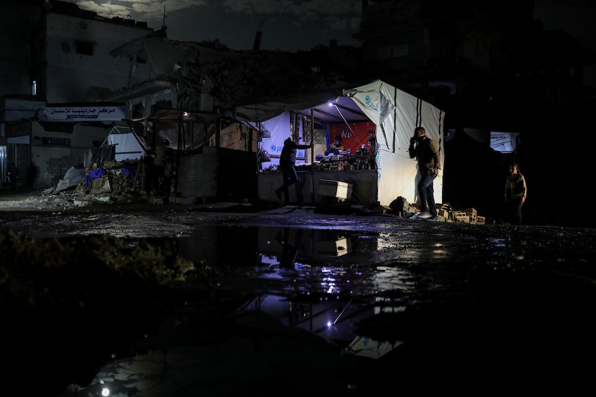 يعيش الفلسطينيون حياتهم اليومية ليلاً في خيام نصبت فوق أنقاض المباني المدمرة في حي الشيخ رضوان وسط مدينة غزة، 5 ديسمبر/كانون الأول 2025.تصوير: عمر أشتوي