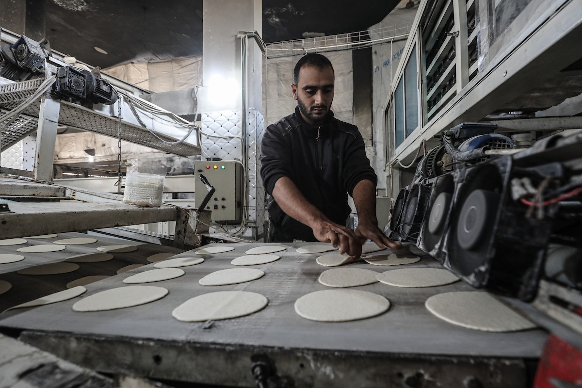عمال فلسطينيون يعيدون تشغيل أحد أقدم المخابز في مخيم النصيرات للاجئين بعد إغلاقه لمدة عامين بسبب الحرب (31).jpg