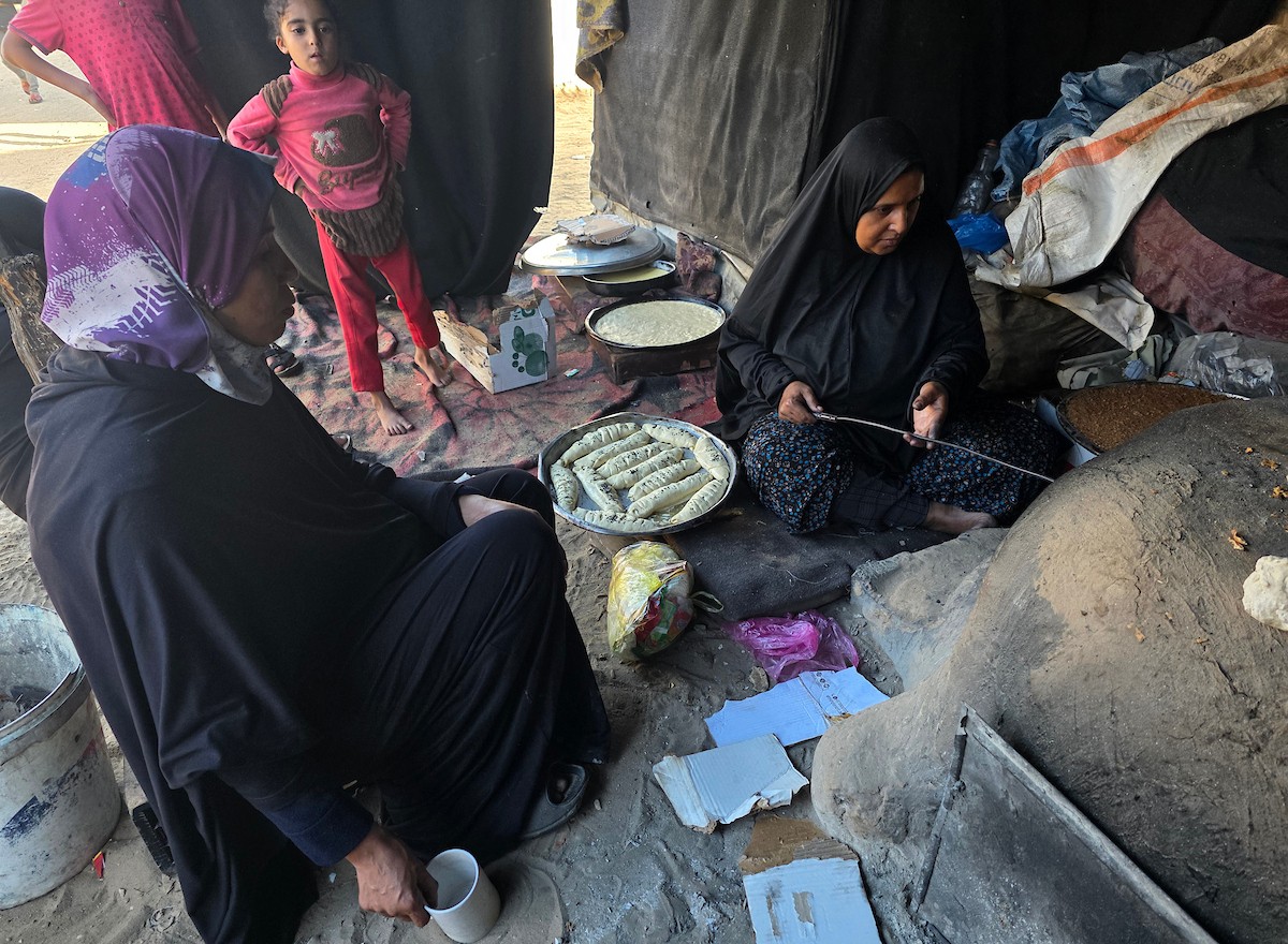 يتجمع فلسطينيون حول أفران طينية مؤقتة لطهي الطعام في قطاع غزة، بعد عشرة أسابيع من وقف إطلاق النار، في ظل شحّ غاز الطهي بسبب القيود الإسرائيلية على دخوله إلى القطاع