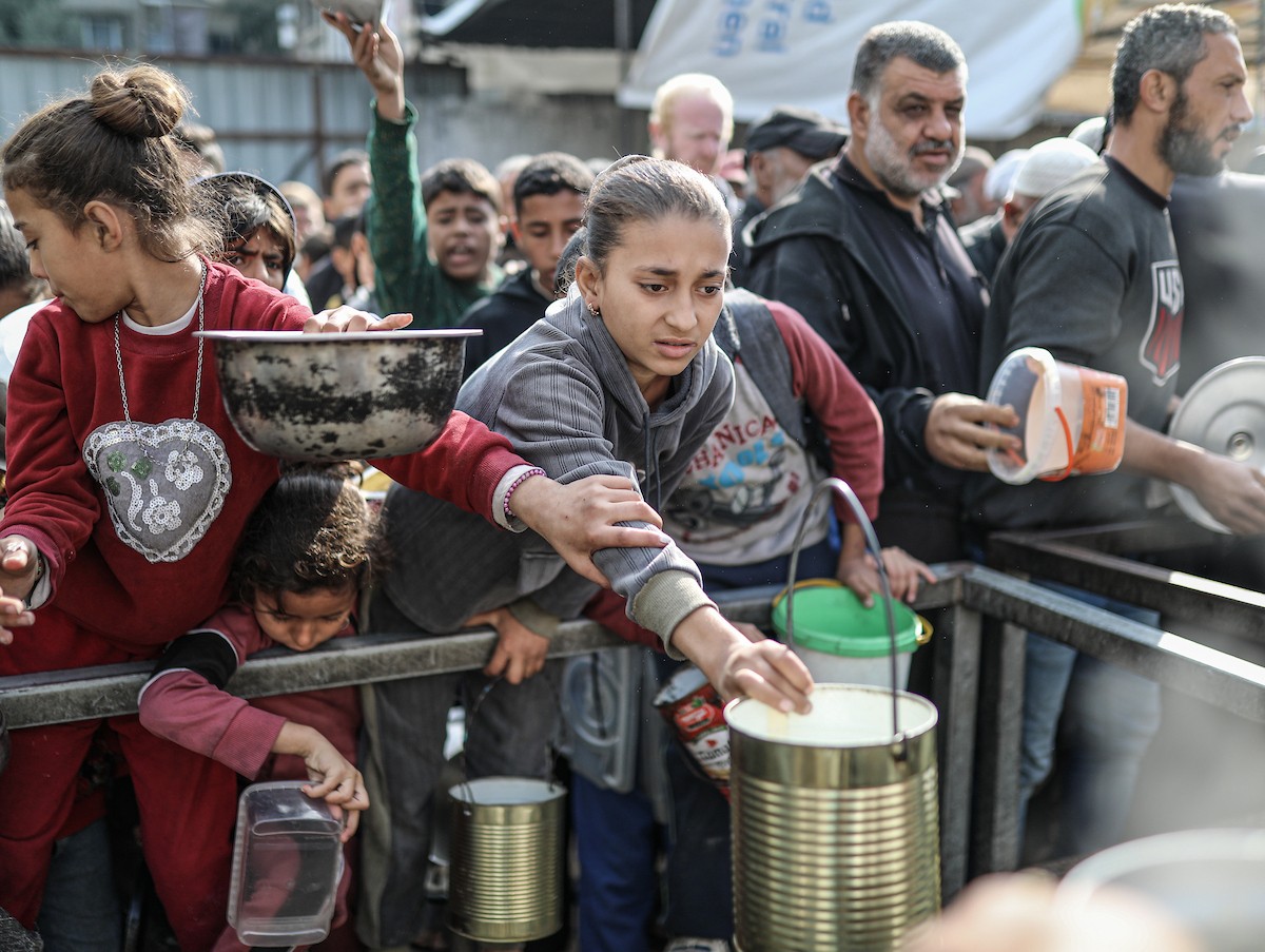 يصطفّ فلسطينيون لتلقّي الطعام من مطبخ خيري في تجمع للنازحين بمخيم النصيرات للاجئين، وسط قطاع غزة. ١٧ ديسمبر/كانون الأول ٢٠٢٥. تصوير: رمزي أبو عامر / (apa)