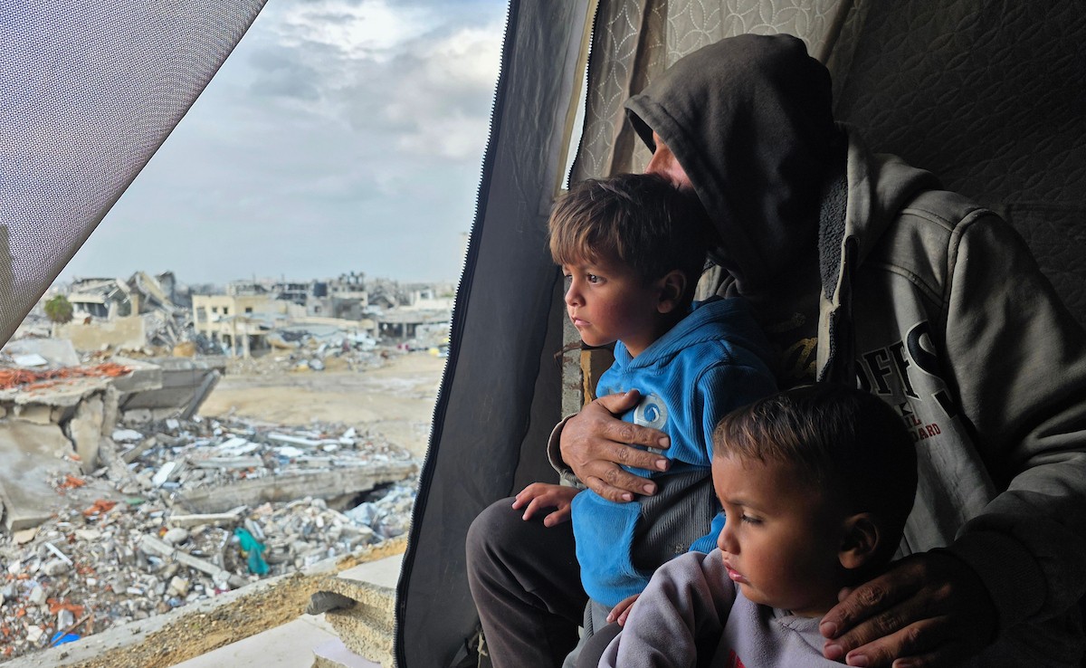 عائلة فلسطينية تحتمي من برد الشتاء القارس في خيمة نصبتها فوق منزلها المدمر قرب الخط الأصفر في خان يونس، جنوب قطاع غزة، ١٧ ديسمبر/كانون الأول ٢٠٢٥. تصوير: طارق محمد/وكالة الأنباء الفلسطينية (APA )