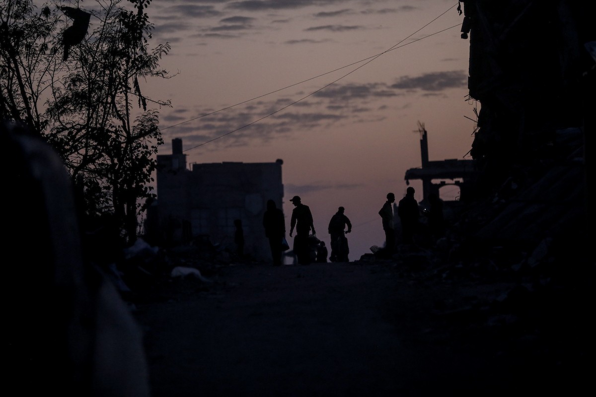 يعيش الفلسطينيون حياتهم اليومية ليلاً في خيام نصبت فوق أنقاض المباني المدمرة في حي الشيخ رضوان وسط مدينة غزة، 5 ديسمبر/كانون الأول 2025.تصوير: عمر أشتوي