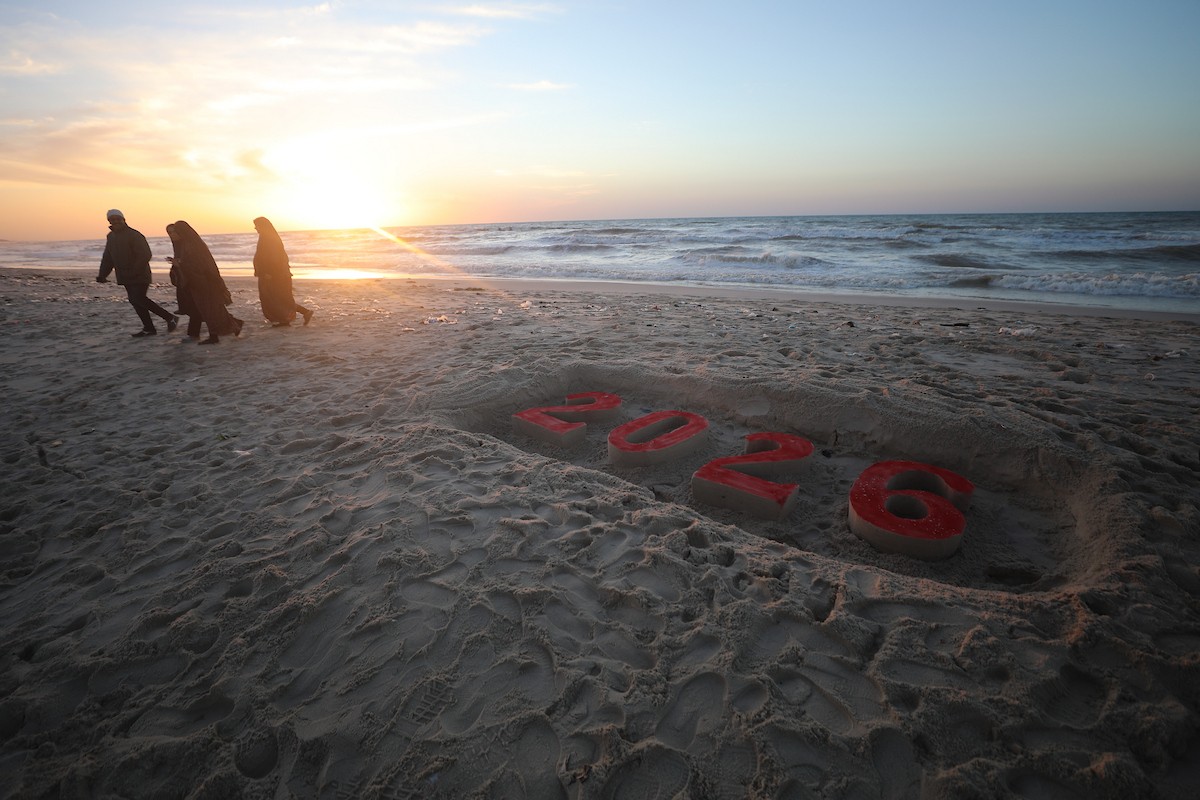 فلسطينيون يودعون عام 2025 بكتابة 2026 على رمال شاطئ غزة، 31 ديسمبركانون الأول 2025. صورة عمر أشتوي