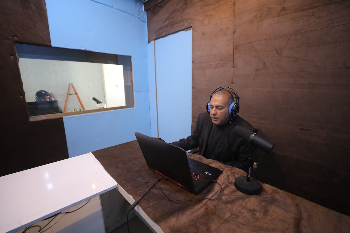 مذيع راديو فلسطيني يبث عبر الإنترنت من استوديوهات إذاعة صوت القدس في غزة، 24 يناير/كانون الثاني 2026. عادت الإذاعة إلى البث بعد توقف دام عامين بسبب الحرب، معتمدةً على معدات بسيطة للتواصل مع الجمهور المحلي ونقل الأخبار عن الأوضاع الإنسانية في القطاع. صورة: عمر أشتوي