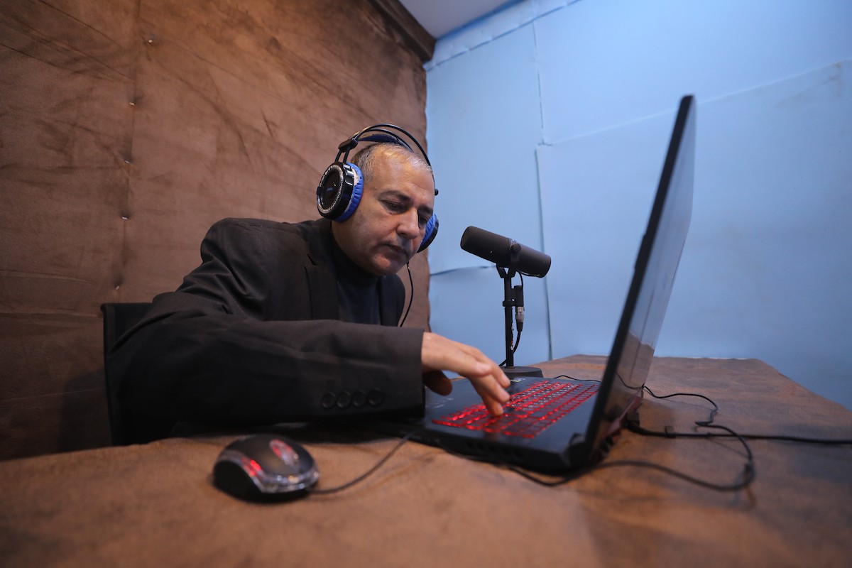 مذيع راديو فلسطيني يبث عبر الإنترنت من استوديوهات إذاعة صوت القدس في غزة، 24 يناير/كانون الثاني 2026. عادت الإذاعة إلى البث بعد توقف دام عامين بسبب الحرب، معتمدةً على معدات بسيطة للتواصل مع الجمهور المحلي ونقل الأخبار عن الأوضاع الإنسانية في القطاع. صورة: عمر أشتوي