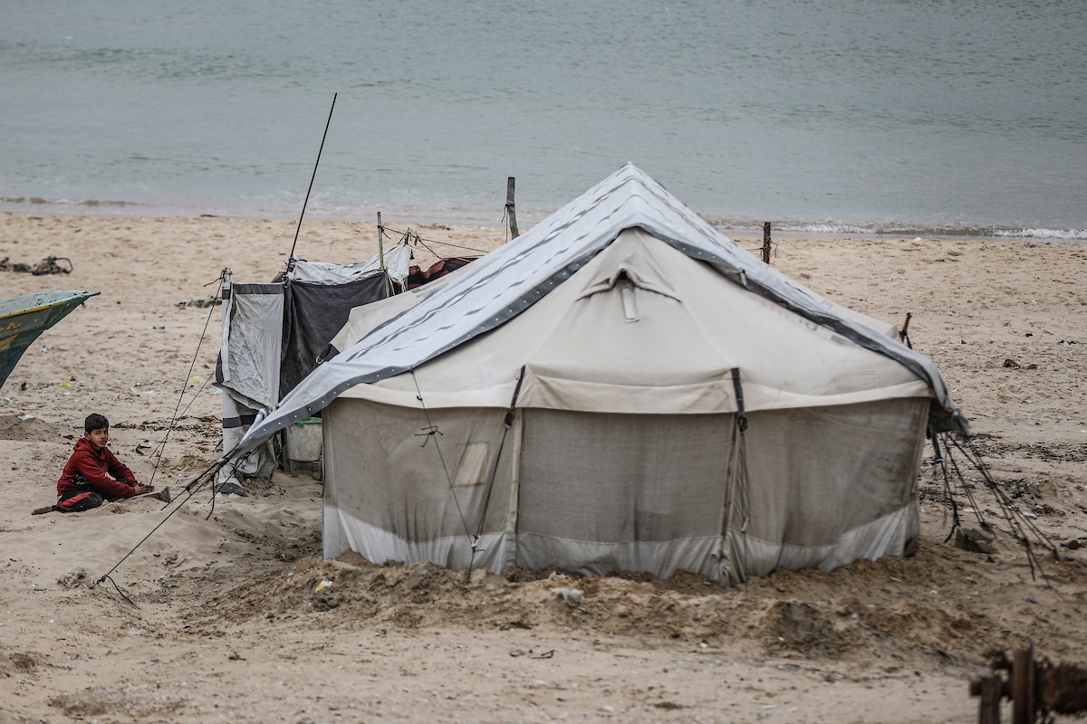 يتفقد فلسطينيون نازحون خيامهم بعد أن تضررت بشدة جراء عاصفة هوائية قوية ضربت مخيمًا للنازحين وسط قطاع غزة. 22 يناير/كانون الثاني 2026. تصوير: رمزي أبو عامر