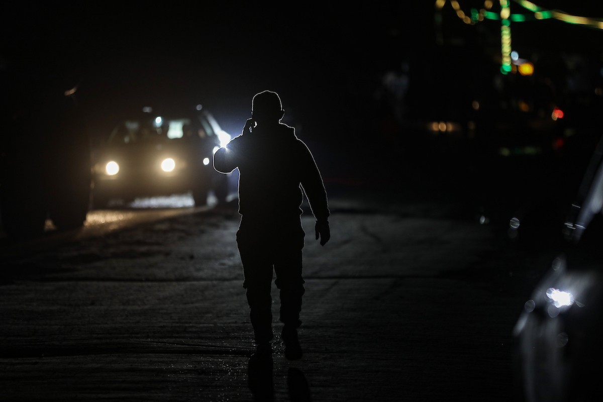 يسير فلسطينيون في أحد شوارع مدينة غزة، بينما يكافح النازحون في خيامهم لمواجهة الظلام، يتدفؤون ويطهون طعامهم بالحطب، محرومين حتى من أبسط مقومات الحياة، 19 يناير/كانون الثاني 2026. صورة: عمر أشتوي