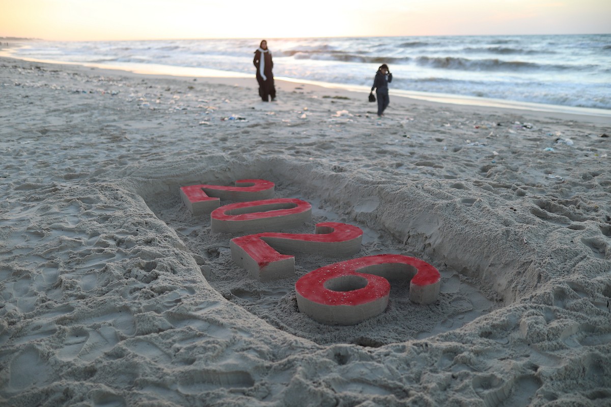 فلسطينيون يودعون عام 2025 بكتابة 2026 على رمال شاطئ غزة، 31 ديسمبركانون الأول 2025. صورة عمر أشتوي