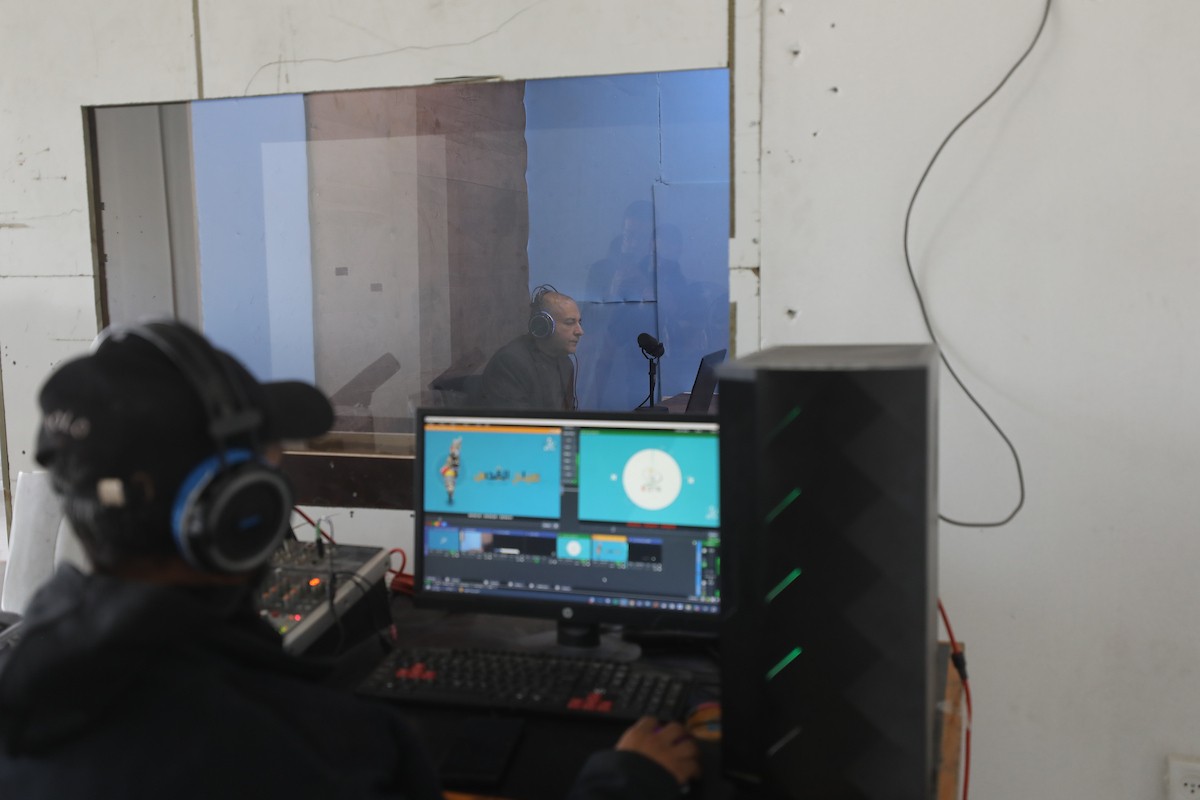 مذيع راديو فلسطيني يبث عبر الإنترنت من استوديوهات إذاعة صوت القدس في غزة، 24 يناير/كانون الثاني 2026. عادت الإذاعة إلى البث بعد توقف دام عامين بسبب الحرب، معتمدةً على معدات بسيطة للتواصل مع الجمهور المحلي ونقل الأخبار عن الأوضاع الإنسانية في القطاع. صورة: عمر أشتوي