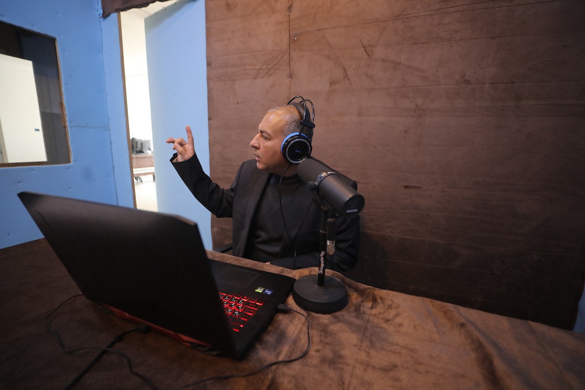 مذيع راديو فلسطيني يبث عبر الإنترنت من استوديوهات إذاعة صوت القدس في غزة، 24 يناير/كانون الثاني 2026. عادت الإذاعة إلى البث بعد توقف دام عامين بسبب الحرب، معتمدةً على معدات بسيطة للتواصل مع الجمهور المحلي ونقل الأخبار عن الأوضاع الإنسانية في القطاع. صورة: عمر أشتوي