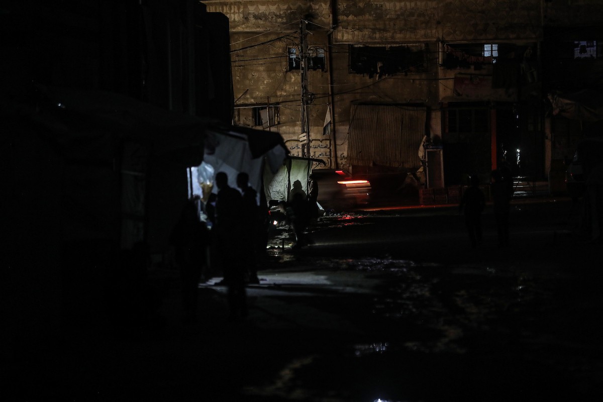 يسير فلسطينيون في أحد شوارع مدينة غزة، بينما يكافح النازحون في خيامهم لمواجهة الظلام، يتدفؤون ويطهون طعامهم بالحطب، محرومين حتى من أبسط مقومات الحياة، 19 يناير/كانون الثاني 2026. صورة: عمر أشتوي