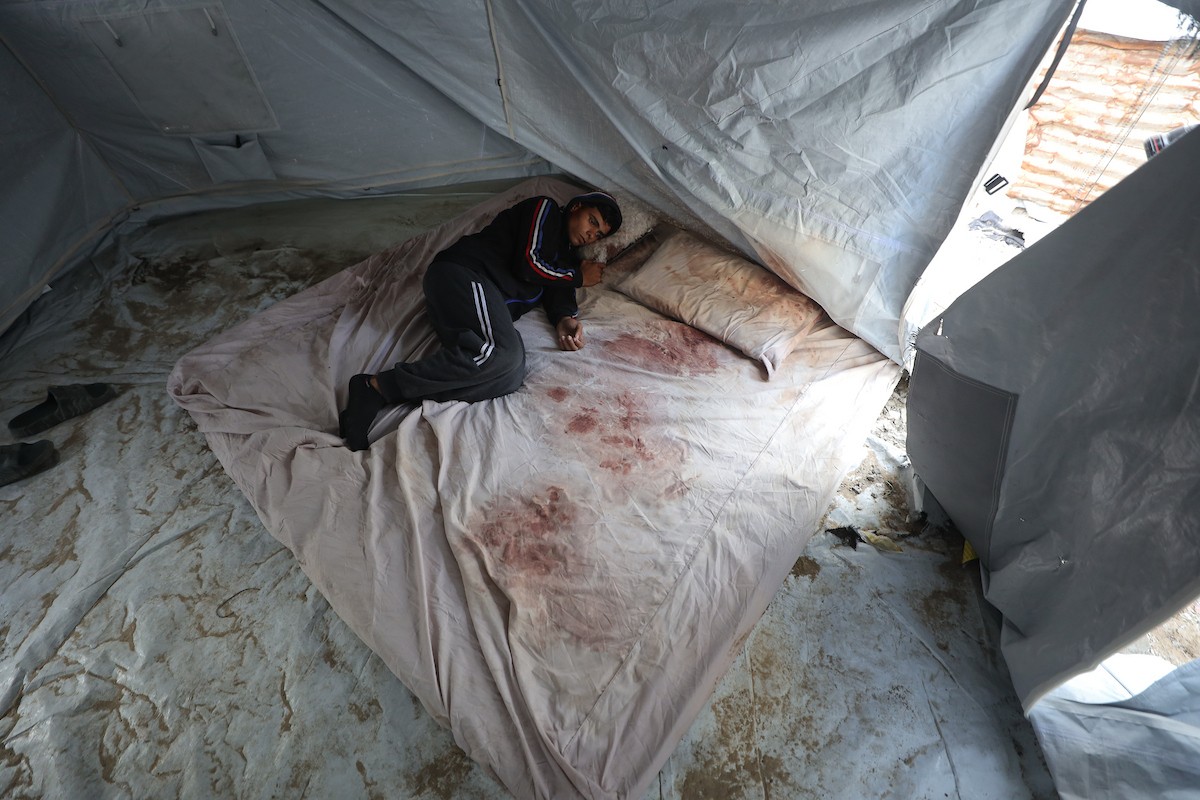 يكافح الشاب الفلسطيني أحمد أبو سعادة، البالغ من العمر عشرين عامًا، من أجل البقاء في خيمة مؤقتة بعد أن فقد زوجته، ولاء جحا، بعد ثلاثة أيام فقط من زفافهما، إثر غارة جوية إسرائيلية على غزة، 7 يناير/كانون الثاني 2025. صورة: عمر أشتوي