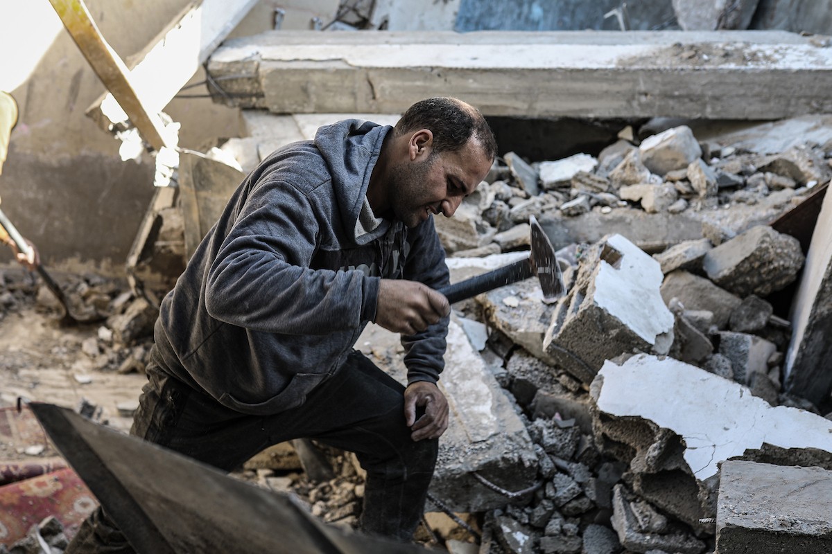 فلسطينيون يتفقدون منزلاً (تضرر سابقاً جراء غارة جوية إسرائيلية) انهار على سكانه، ما أسفر عن وفاة رجل ونجله الصغير في مخيم المغازي للاجئين وسط قطاع غزة، 5 يناير/كانون الثاني 2026. صورة: رمزي أبو عامر