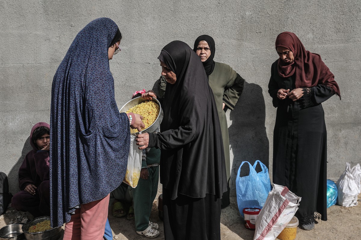 أطفال فلسطينيون ينتظرون وجبة ساخنة، توزعها إحدى المنظمات الخيرية، في ظل استمرار أزمة الغذاء بسبب محدودية المساعدات الإنسانية في مخيم النصيرات للاجئين وسط قطاع غزة، في 10 يناير/كانون الثاني 2026. صورة: معز صالحي