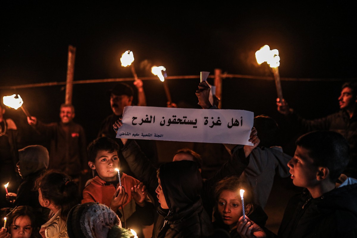 أطفال في وقفة احتجاجية في مخيم الشاطئ غرب مدينة غزة ليلة رأس السنة الميلادية 2026، 1 يناير/كانون الثاني 2026. تصوير: عمر أشتوي