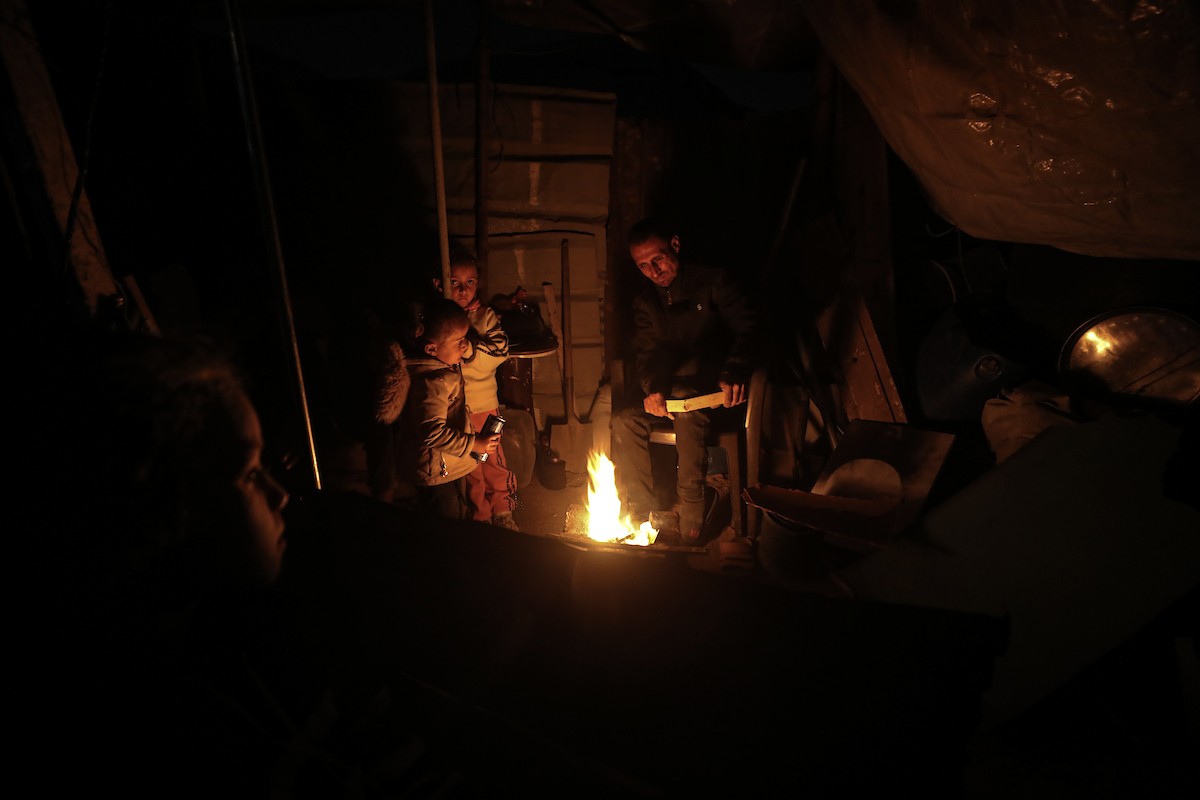 عائلات تعيش في خيام مؤقتة وسط الأنقاض تشعل نيرانًا للتدفئة في جباليا، شمال قطاع غزة، في 12 يناير/كانون الثاني 2026. ويكافح الفلسطينيون الذين دُمرت منازلهم في هجمات إسرائيلية من أجل البقاء في ظل ظروف شتوية قاسية وبرد قارس. صورة: عمر أشتوي