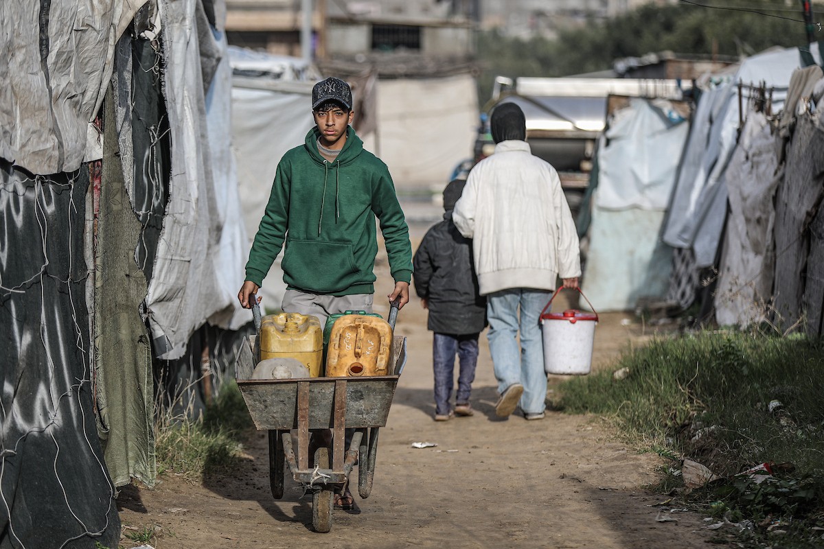 يملأ الفلسطينيون خزاناتهم بالمياه التي توزعها صهاريج المياه، وينقلونها إلى خيامهم في مخيم النصيرات وسط قطاع غزة، حيث تفاقمت أزمة المياه نتيجة الأضرار الجسيمة التي لحقت بالبنية التحتية جراء الهجمات الإسرائيلية، 29 يناير/كانون الثاني 2026. صورة: رمزي أبو عامر