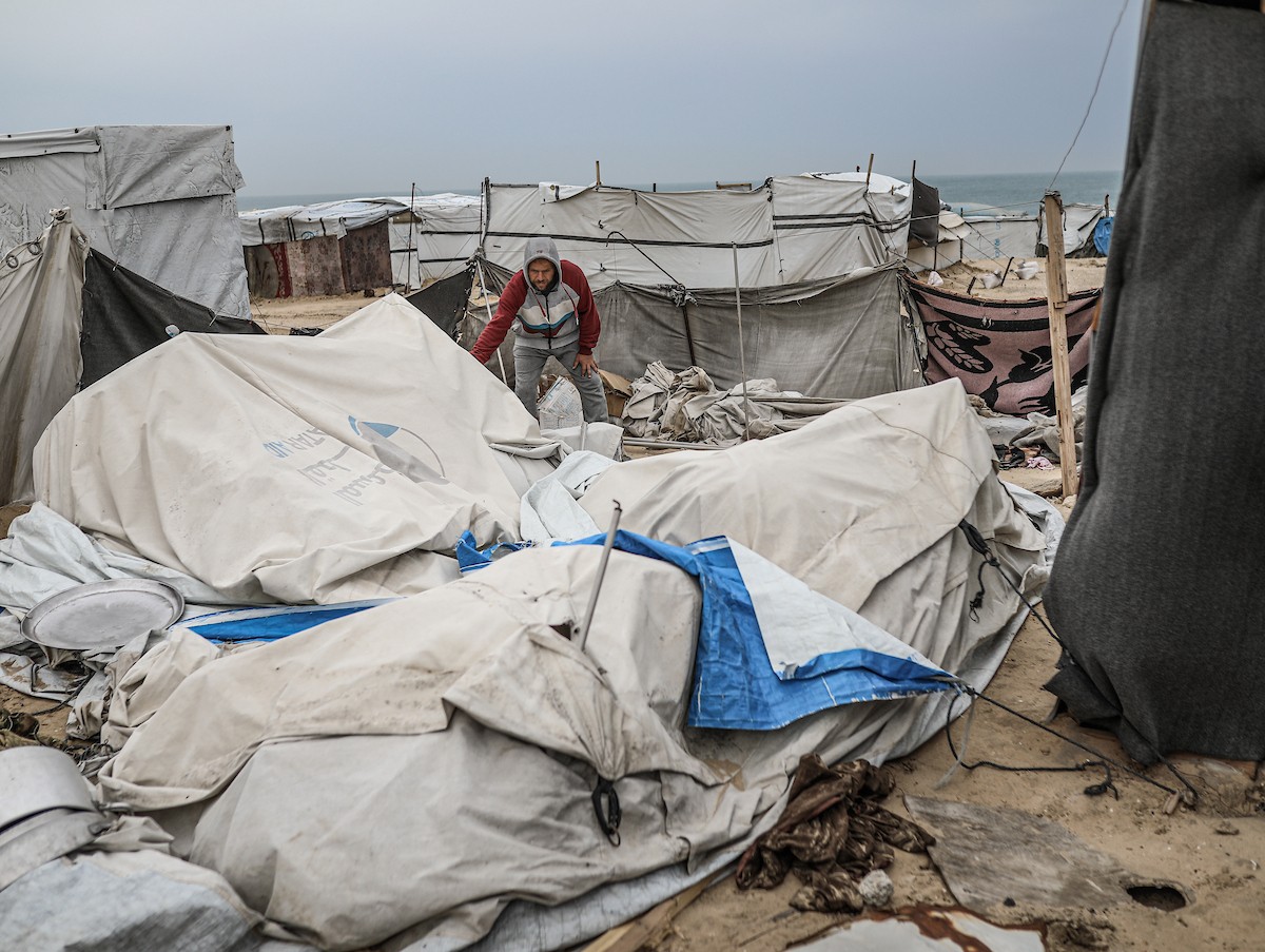 يتفقد فلسطينيون نازحون خيامهم بعد أن تضررت بشدة جراء عاصفة هوائية قوية ضربت مخيمًا للنازحين وسط قطاع غزة. 22 يناير/كانون الثاني 2026. تصوير: رمزي أبو عامر
