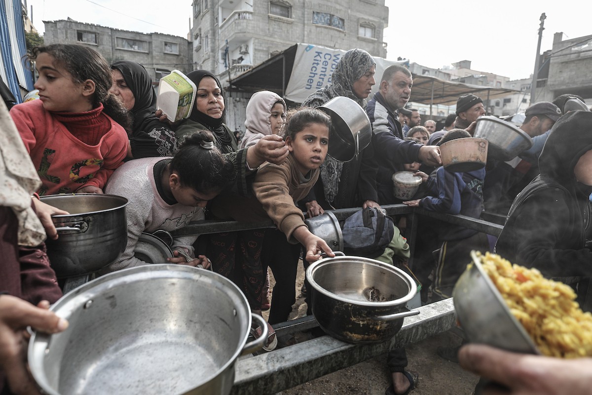 أطفال فلسطينيون ينتظرون وجبة ساخنة، توزعها إحدى المنظمات الخيرية، في ظل استمرار أزمة الغذاء بسبب محدودية المساعدات الإنسانية في مخيم النصيرات للاجئين وسط قطاع غزة، في 10 يناير/كانون الثاني 2026. صورة: معز صالحي