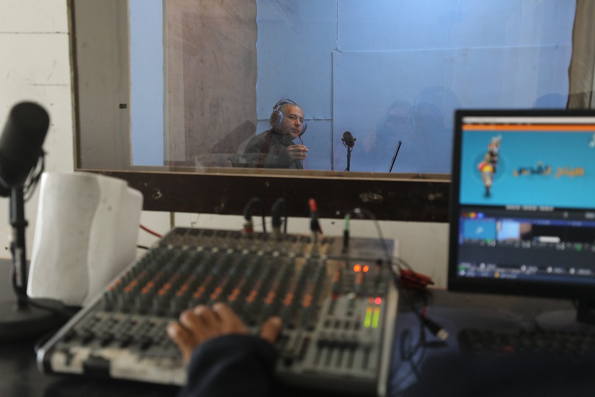 مذيع راديو فلسطيني يبث عبر الإنترنت من استوديوهات إذاعة صوت القدس في غزة، 24 يناير/كانون الثاني 2026. عادت الإذاعة إلى البث بعد توقف دام عامين بسبب الحرب، معتمدةً على معدات بسيطة للتواصل مع الجمهور المحلي ونقل الأخبار عن الأوضاع الإنسانية في القطاع. صورة: عمر أشتوي