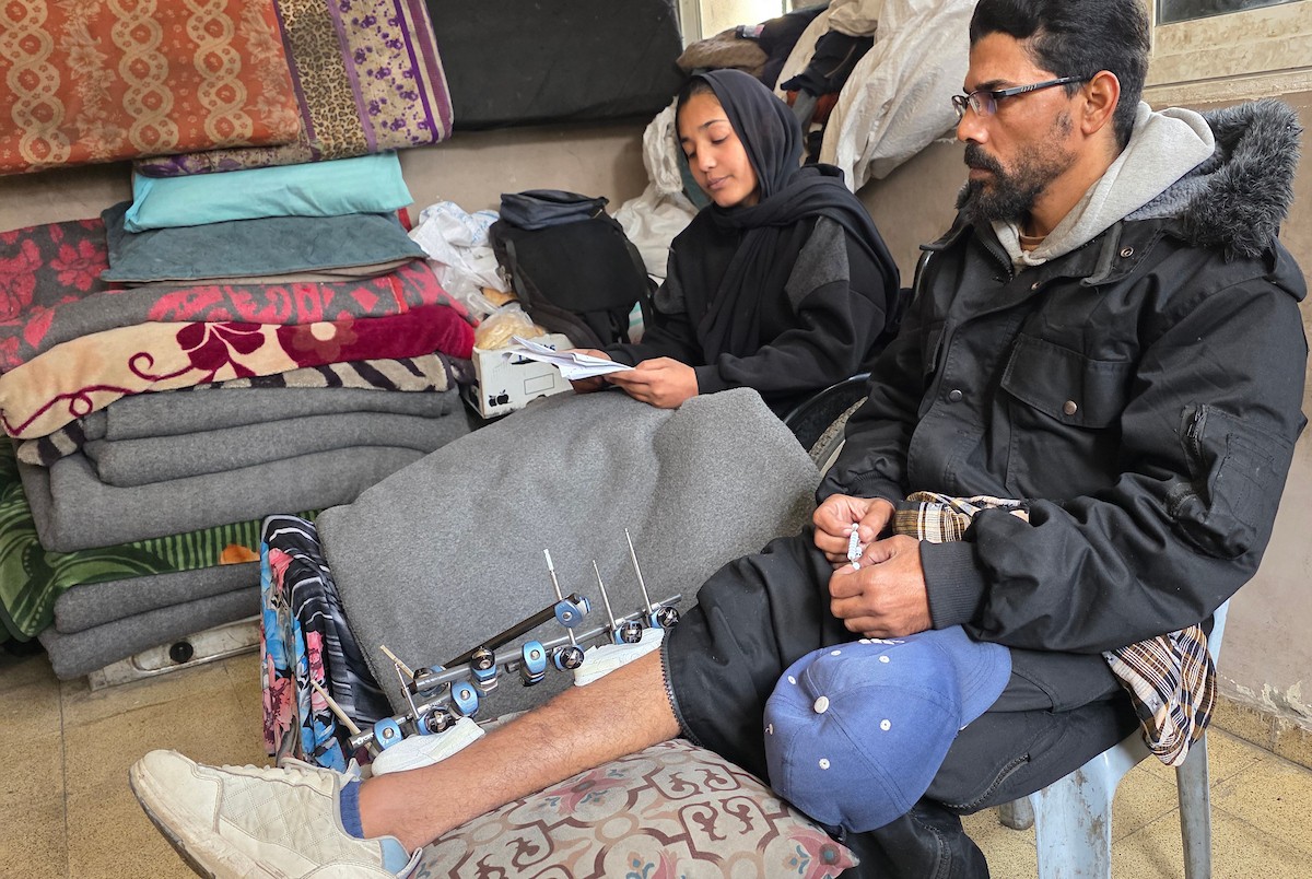 ريماس أبو لحية ووالدها مصابان بساقيهما برصاص الجيش الإسرائيلي، وينتظران السفر لاستكمال العلاج خارج قطاع غزة، خان يونس، 25 يناير/كانون الثاني 2026. تصوير: طارق محمد/ (APA Images)